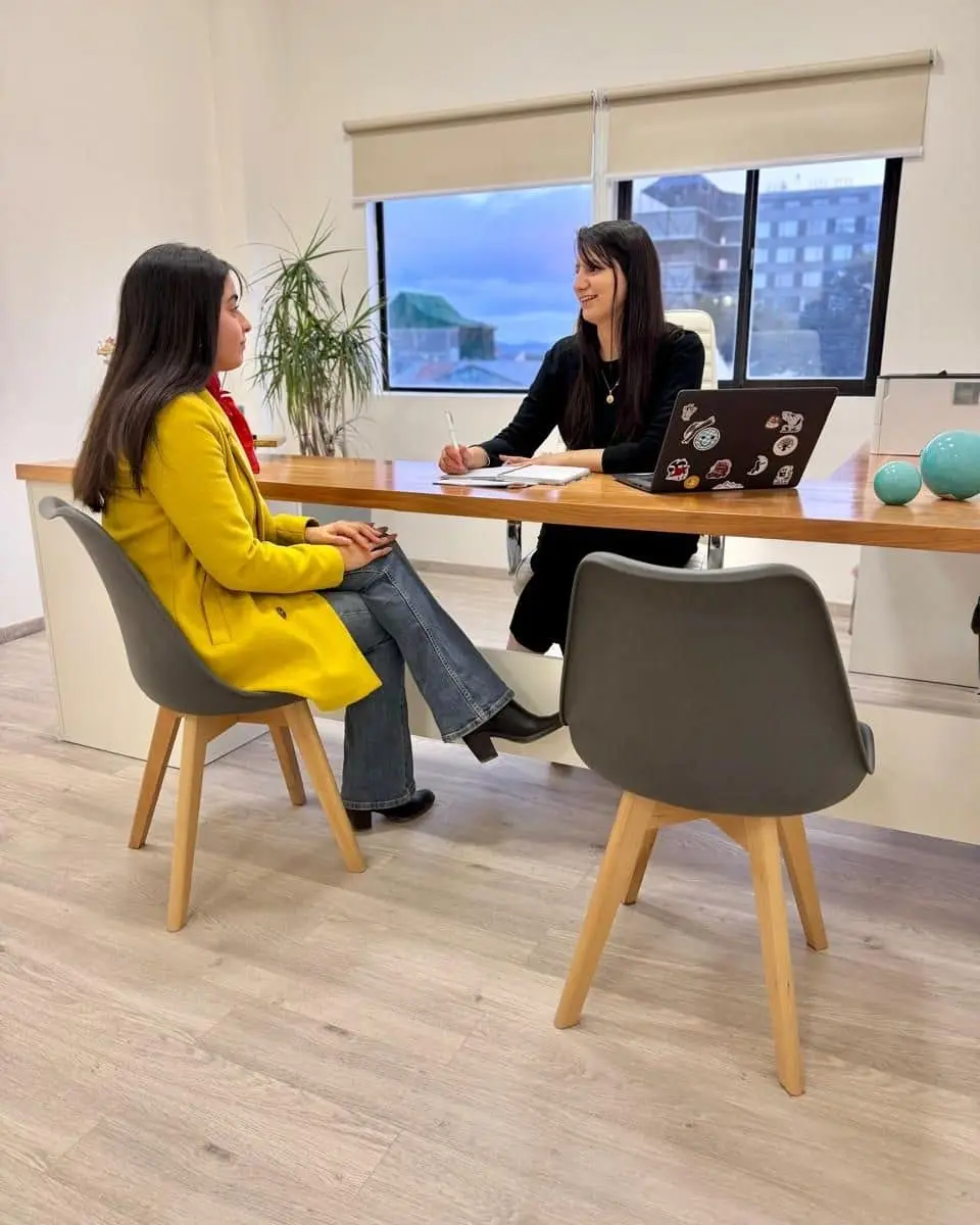 Una profesional de LegalMente conversa con una clienta sentada frente a su escritorio, en la oficina de Ushuaia